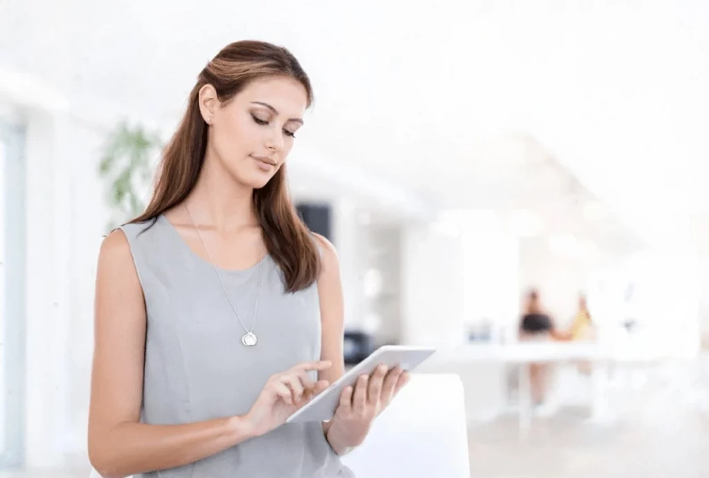 Hôtesse d'accueil consultant une tablette tactile dans un hall lumineux