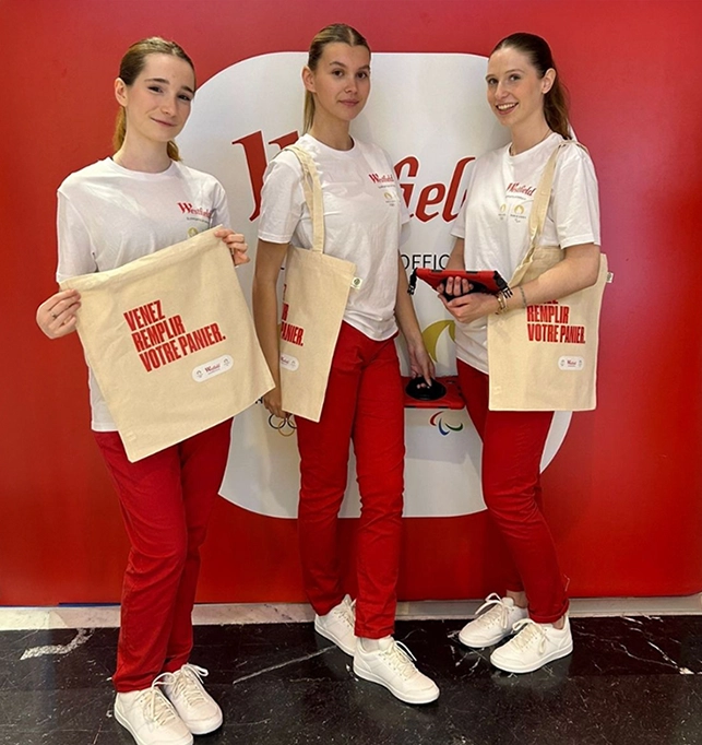 Trois hôtesses en tenue coordonnée présentant des tote bags lors d'une animation