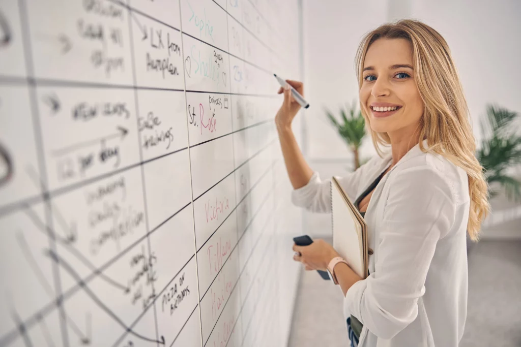 Femme souriante planifiant un emploi du temps sur un tableau blanc au bureau