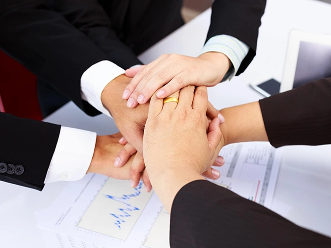 Mains d'une équipe réunies au-dessus d'une table de travail