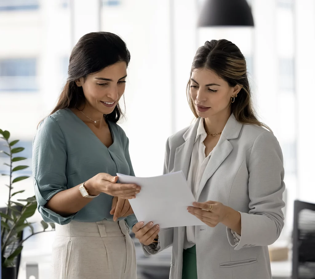 Deux collaboratrices échangeant autour d'un document dans un bureau lumineux