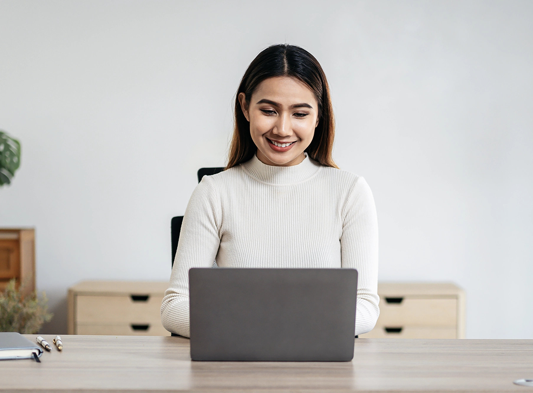Jeune femme souriante travaillant sur un ordinateur portable à son bureau