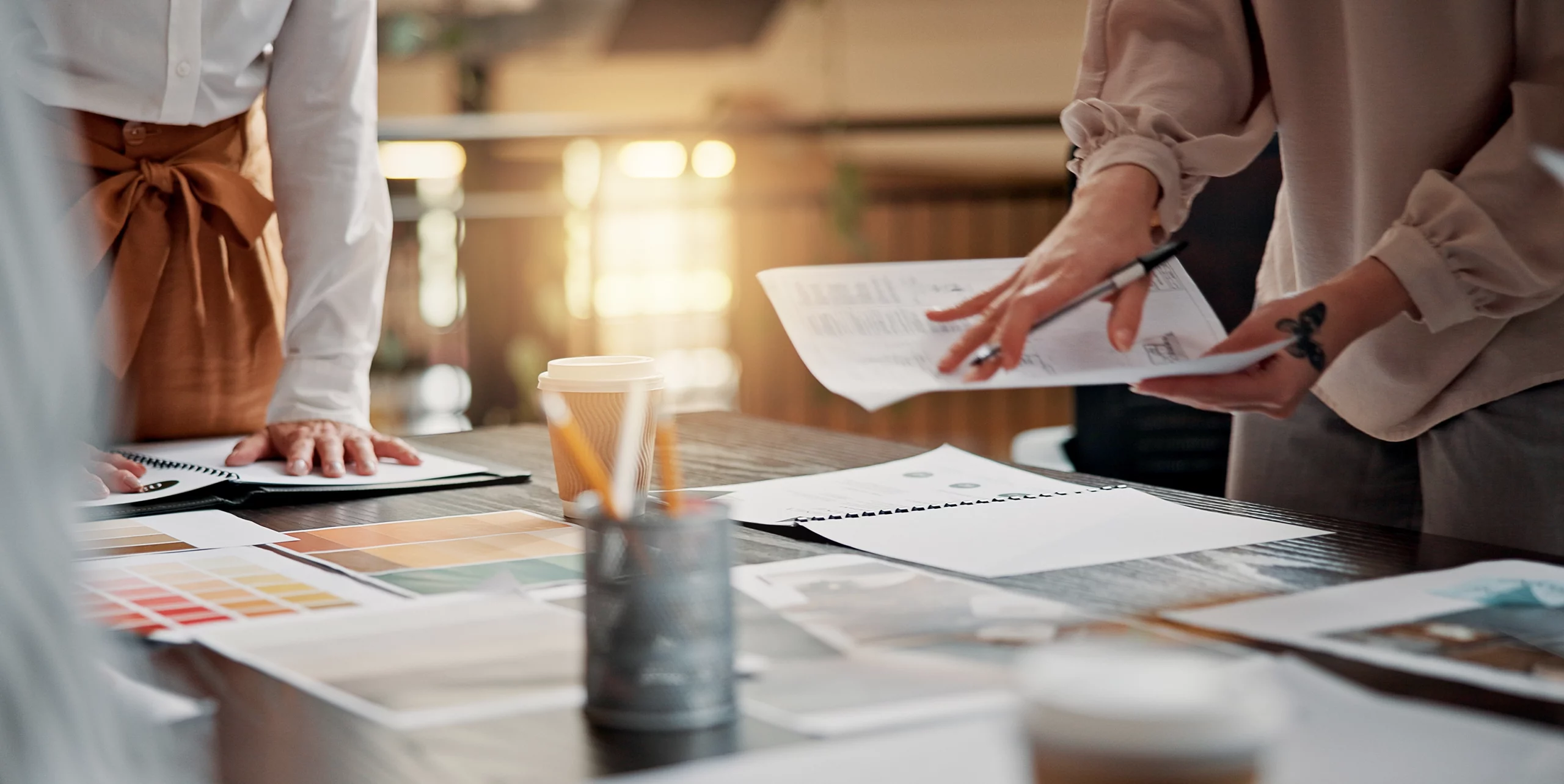 Deux personnes analysant des documents et nuanciers de couleurs sur un bureau